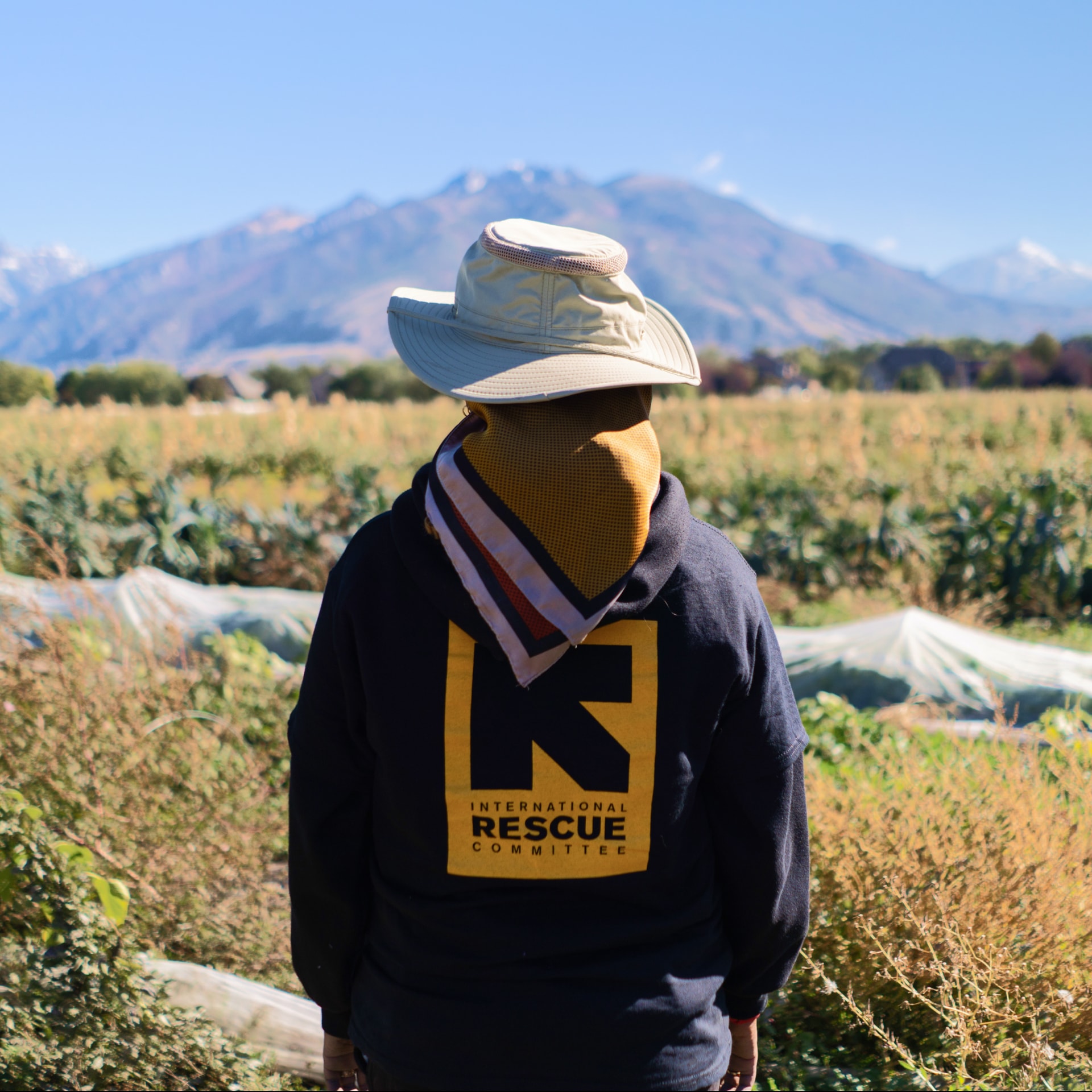 An immigrant family member in an IRC hoodie standing in a Utah field
