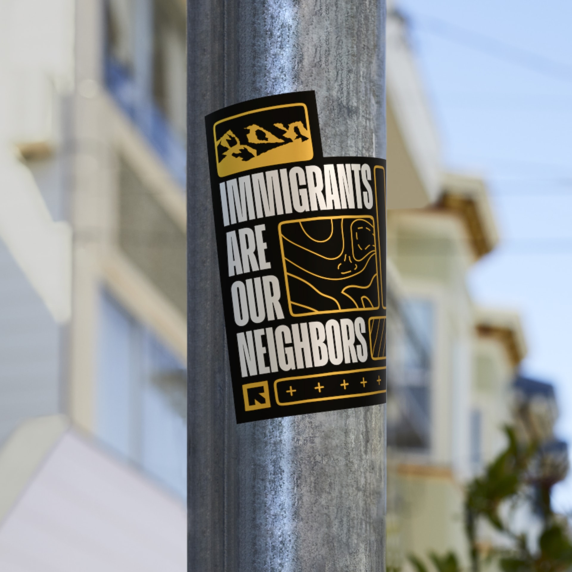 An 'Immigrants Are Our Neighbors' sticker applied to a city pole